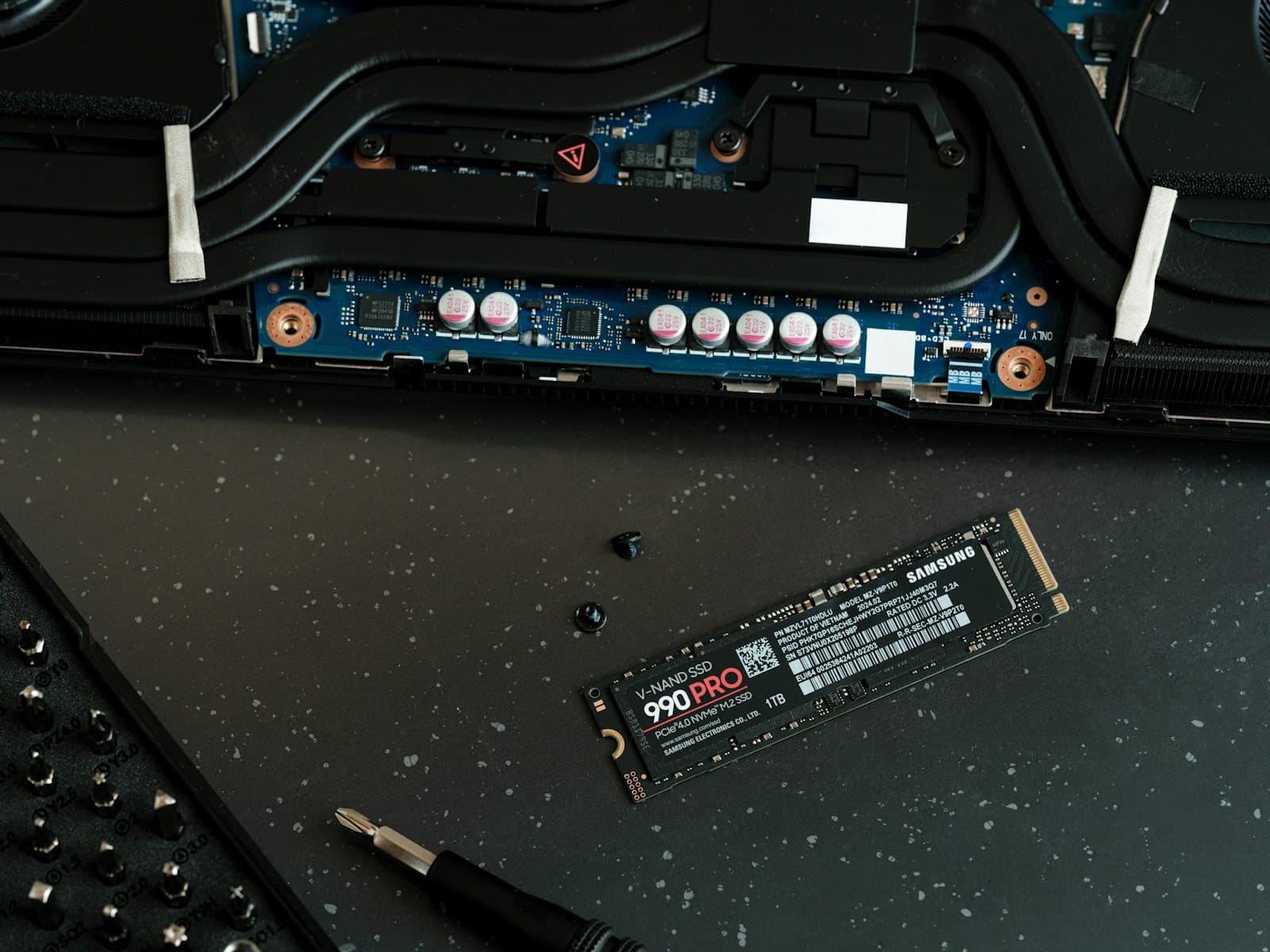 Opened laptop with a replacement solid-state drive and repair tools